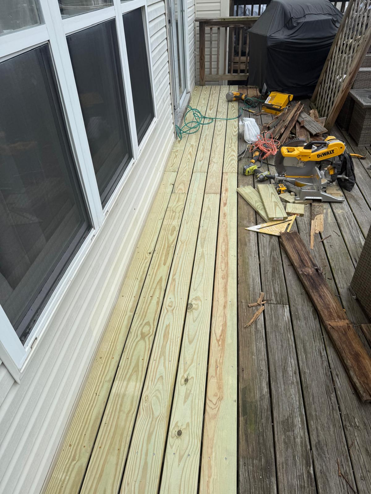 New pressure-treated deck boards next to weathered planks
